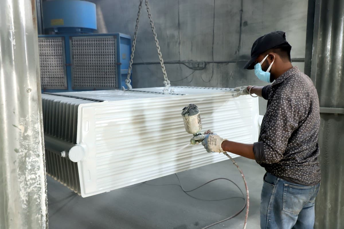 Worker spray-painting a finished radiator