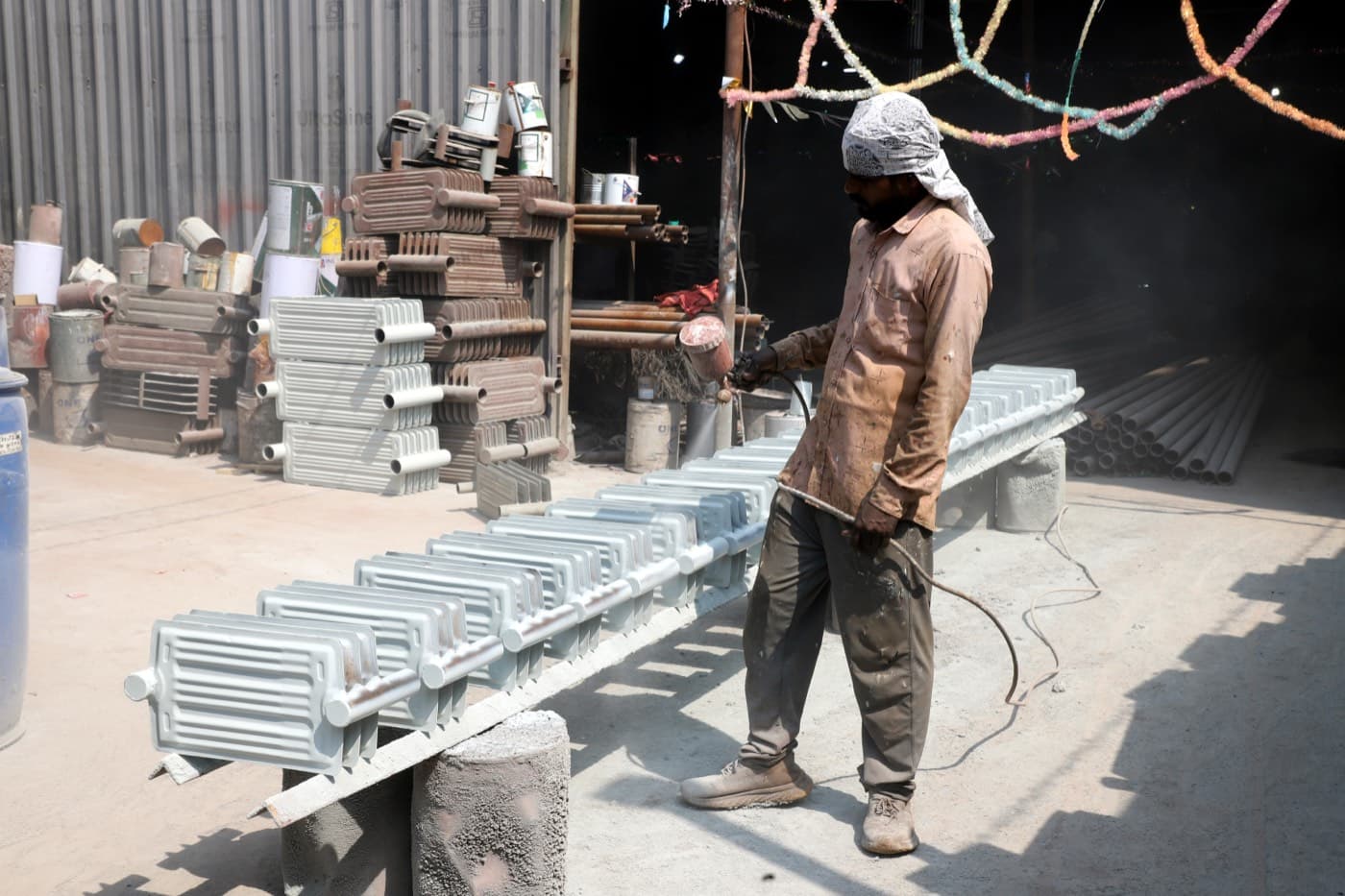 Worker spray-painting a finished transformer radiator