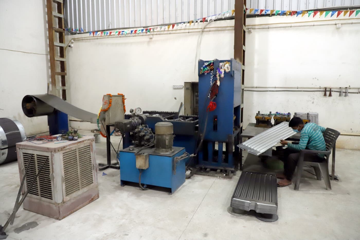 Raw sheet steel staged beside the panel-forming machine