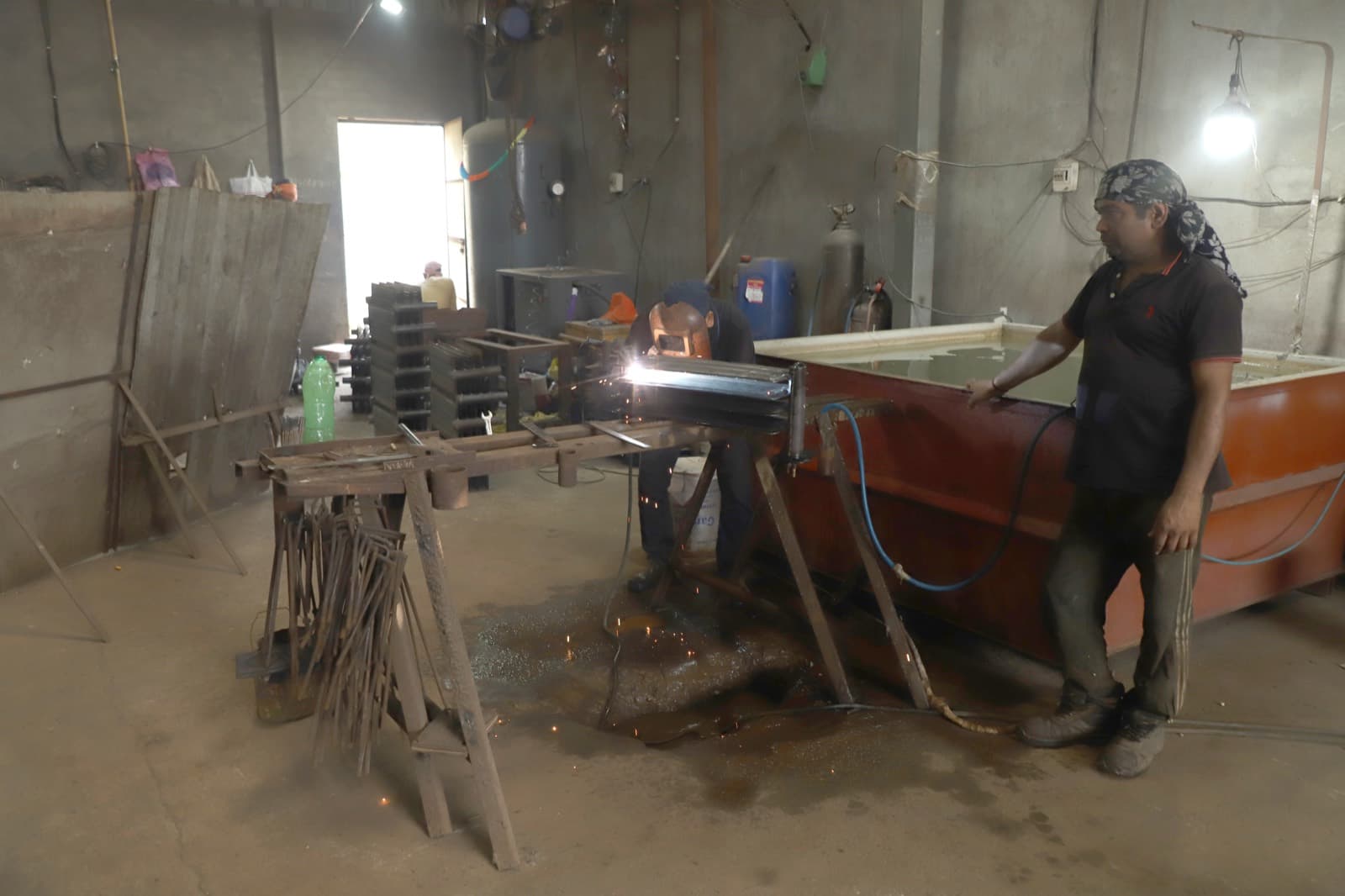 Fabricator welding a custom transformer radiator assembly on the shop floor